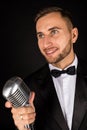 Portrait of handsome man sing on microphone on black background. Royalty Free Stock Photo