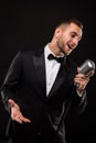 Portrait of handsome man sing on microphone on black background Royalty Free Stock Photo