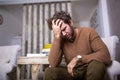 Portrait of an handsome man sitting on a sofa at home with a headache, feeling pain and with an expression of being unwell. Royalty Free Stock Photo