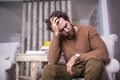 Portrait of an handsome man sitting on a sofa at home with a headache, feeling pain and with an expression of being unwell. Royalty Free Stock Photo