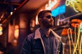 Portrait of a handsome man standing in the night on the street. Illuminated signboards, neon, lights. Royalty Free Stock Photo