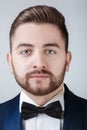 Portrait of handsome man in tuxedo and bow tie looking at camera. Fashionable, festive clothing. emcee on grey Royalty Free Stock Photo