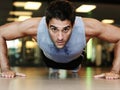 Feeling the burn. Portrait of a handsome man wearing sports clothing doing pushups at the gym. Royalty Free Stock Photo