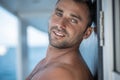 Portrait of handsome man with white teeths smile, blue eyes, surfer and blue ocean