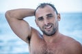 Portrait of handsome man with white teeths smile, blue eyes, wet body, surfer and blue ocean