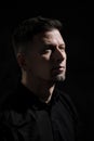 Portrait of a handsome man 40 years old on a dark artistic background close-up. Brunette, with gray hair, black beard Royalty Free Stock Photo