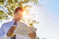 Portrait of handsome mature businessman holding cup of coffee while reading newspaper in park during break Royalty Free Stock Photo