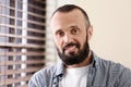 Portrait of handsome mature man near window with blinds Royalty Free Stock Photo