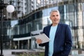 Portrait of handsome mature man with tablet in city center Royalty Free Stock Photo