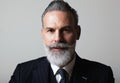 Portrait of handsome middle aged bearded gentleman wearing trendy suit over empty gray background. Studio shot, business