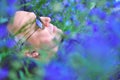 Portrait of handsome middle-aged man lying on field among blue flowers. Pensive calm man in profile over nature outdoor Royalty Free Stock Photo