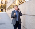 Portrait of handsome middle aged smart businessman walking in the city talking on mobile phone Royalty Free Stock Photo