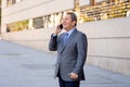 Portrait of handsome middle aged smart businessman walking in the city talking on mobile phone Royalty Free Stock Photo