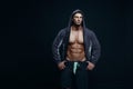 Portrait of a handsome muscular bodybuilder in hoodie posing over black background.