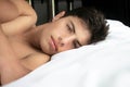 Portrait of handsome muscular hispanic latino male lying on pillow and looking directly at camera