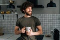 Portrait of handsome pensive young man holding in hand cup with morning coffee, thoughtful looking out window, standing Royalty Free Stock Photo