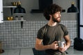 Portrait of handsome pensive young man holding in hand cup with morning coffee, thoughtful looking out window, standing Royalty Free Stock Photo