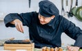 Portrait handsome professional Japanese male chef wearing black uniform, hat, cooking, making takoyaki street food, smiling with