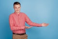 Portrait of handsome reliable guy hands displaying blank space on blue background