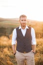 Portrait of handsome retro stylish man, posing on the background of summer field, sunset. Young bearded blond man Royalty Free Stock Photo