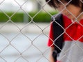 Portrait of handsome sad boy behind fence mesh netting.