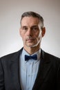 Shot of a Handsome Senior Male dressed in a jacket with the bow tie against light Background Royalty Free Stock Photo