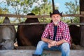Portrait of handsome senior man cattle farmer owner with gray beard wearing cowboy hat sitting smiling and looking at camera in