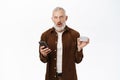 Portrait of handsome senior man, caucasian old guy using smartphone and holding credit card, shopping online, paying Royalty Free Stock Photo