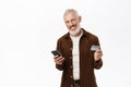 Portrait of handsome senior man, caucasian old guy using smartphone and holding credit card, shopping online, paying Royalty Free Stock Photo