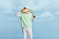 Portrait of handsome senior man in stylish white outfit posing with tennis racket, drinking juice over sky blue Royalty Free Stock Photo