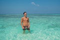 Portrait of handsome sexy young tanned man laughing in the ocean at the beach at the tropical island luxury resort Royalty Free Stock Photo