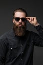 Portrait of handsome s bearded young man with serious expression wearing sunglasses over gray background Royalty Free Stock Photo