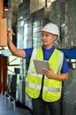 Handsome Asian male warehouse supervisor worker working in warehouse, using tablet Royalty Free Stock Photo