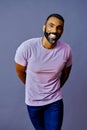 portrait of a handsome smiling african american man with beard and mustache purple shirt on a gray background Royalty Free Stock Photo