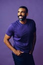 portrait of a handsome smiling man with beard and mustache purple shirt on a gray looking at camera space background Royalty Free Stock Photo