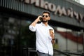 Portrait of handsome smiling man in casual wear holding smartphone. Young businessman talking on the phone, standing on city Royalty Free Stock Photo