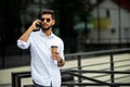 Portrait of handsome smiling man in casual wear holding smartphone. Young businessman talking on the phone, standing on city Royalty Free Stock Photo