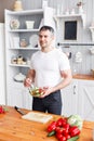 Portrait of handsome smiling man chopping vegetables in the kitchen. The concept of eco-friendly products for cooking. Royalty Free Stock Photo