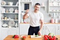 Portrait of handsome smiling man at kitchen. cooking and home concept - close up of male hand chopping cucumber on Royalty Free Stock Photo