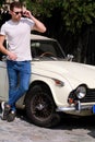 Portrait of a handsome smiling man with sunglasses, male model posing in urban city street next his car. Royalty Free Stock Photo