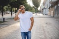 Portrait of handsome smiling stylish model. Man dressed in white T-shirt. Fashion male posing on the street background Royalty Free Stock Photo