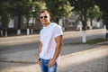 Portrait of handsome smiling stylish model. Man dressed in white T-shirt. Fashion male posing on the street background Royalty Free Stock Photo