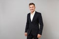 Portrait of handsome smiling young business man in classic black suit, white shirt standing isolated on grey wall Royalty Free Stock Photo