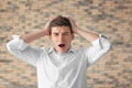 Portrait of handsome stressed young man against brick wall Royalty Free Stock Photo