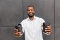 Portrait of handsome stylish man standing outdoors in white shirt and smiling. Happy african american male employee Royalty Free Stock Photo