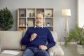 Portrait of handsome and stylish unshaven bald senior man sitting on sofa in home office. Royalty Free Stock Photo