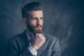 Portrait of handsome stylish young man with mustache, beard and beautiful hairstyle keep calm and think while hold beard Royalty Free Stock Photo