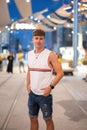 Portrait of handsome stylish young man wearing sleeveless shirt and jeans shorts posing on city street at night Royalty Free Stock Photo