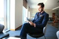 Portrait of handsome successful man drink coffee and look to the digital tablet screen sitting in coffee shop, business Royalty Free Stock Photo