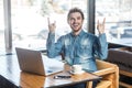 Portrait of handsome successfull positive bearded young freelancer in blue jeans shirt are sitting in cafe and working on laptop